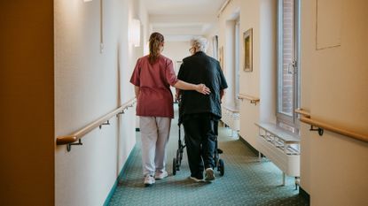 A stock photo of a nurse assisting a woman with a walker. 