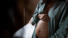 Pregnant woman holding bump in dark room